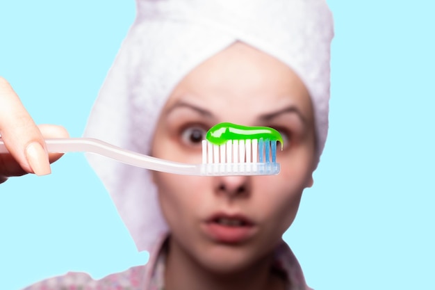 schöne Frau, die eine Zahnbürste mit blauem Hintergrund der Zahnpasta hält