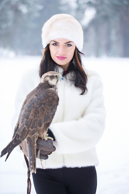 Schöne Frau, die einen Falken auf ihrer Hand im Winter hält