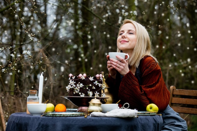 Schöne Frau, die einen Tee in einem Garten trinkt