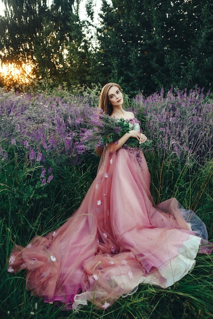 Schöne Frau, die elegantes Kleid trägt, das mit Blumen aufwirft