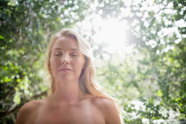 Schöne Frau, die gegen helles Sonnenlicht meditiert