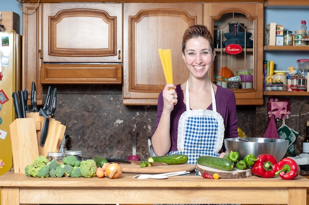 schöne Frau, die Gemüse mit Spaghetti kocht