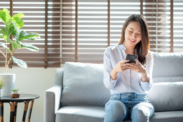 Schöne Frau, die Handy verwendet, um mit ihren Freunden zu Hause zu chatten