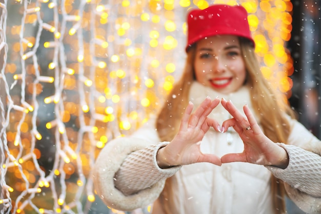 Schöne Frau, die Herz Gymbol gegen Bokeh-Hintergrund zeigt. Freiraum