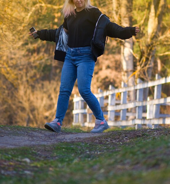 Schöne Frau, die in der Frühlingslandschaft tanzt Blonde Tänzerin im bunten Frühlingspark