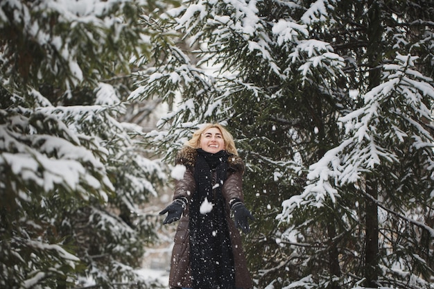 Schöne Frau, die in einem Winterwald aufwirft.