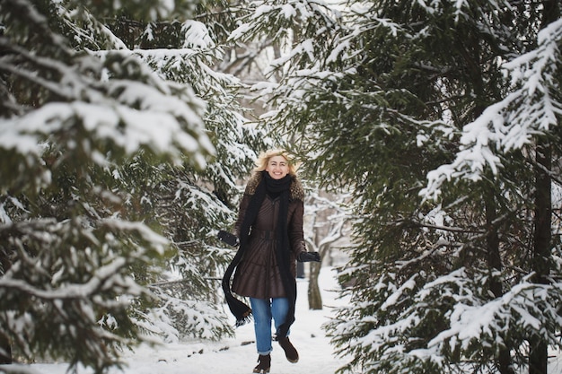 Schöne Frau, die in einem Winterwald aufwirft.