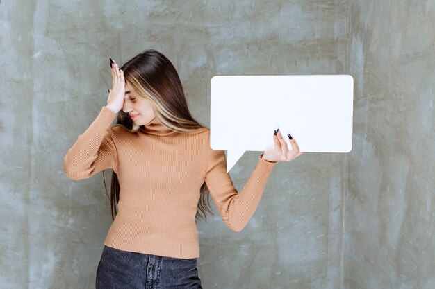 Foto schöne frau, die leere sprechblase auf einer steinmauer hält