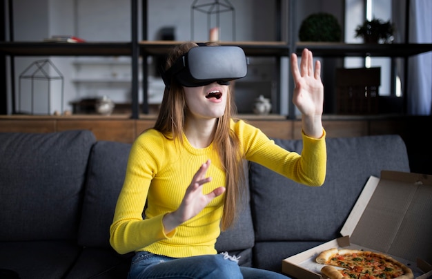 Schöne Frau, die Luft während der VR-Erfahrung berührt. Mädchen isst Pizza