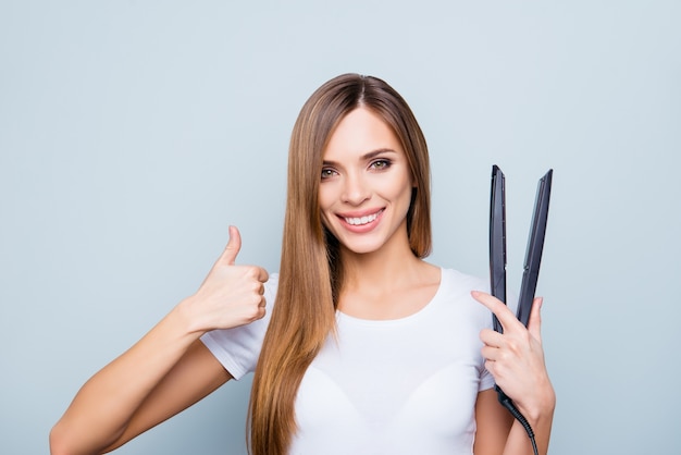 Schöne Frau, die mit Haarglätter aufwirft