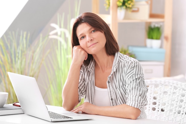 Schöne Frau, die mit Laptop zu Hause arbeitet