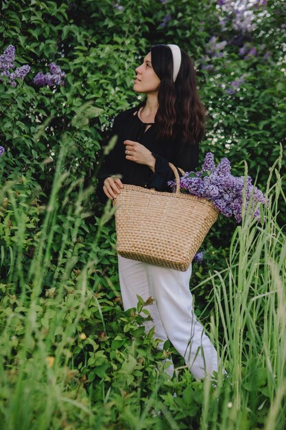 Schöne Frau, die mit lila Blumen posiert, der Sommer kommt