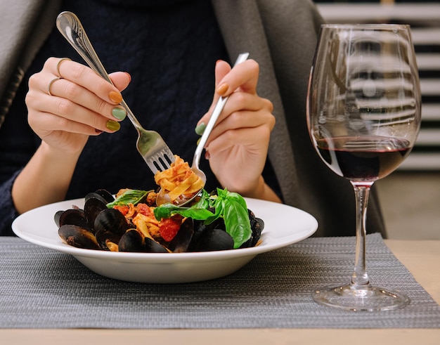 Schöne Frau, die Nudeln mit Muscheln in einem Restaurant isst | Premium ...