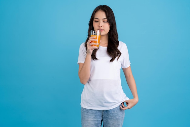 Schöne Frau, die Orange aus einem Glas trinkt