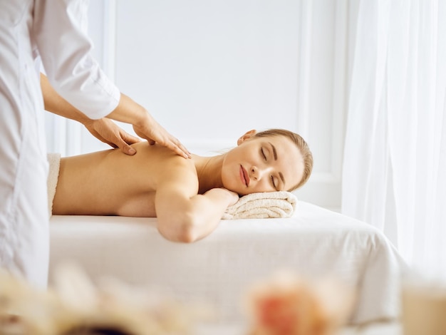 Schöne Frau, die Rückenmassage mit geschlossenen Augen genießt. Spa-Behandlungskonzept.