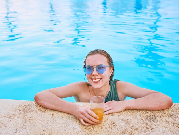 Schöne Frau, die sich am Swimmingpool entspannt Sommererholungsreisekonzept