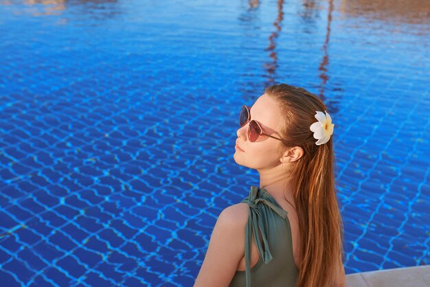 Schöne Frau, die sich am Swimmingpool entspannt Sommererholungsreisekonzept