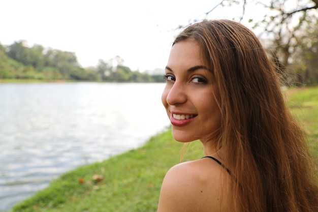 Schöne Frau, die sich entspannt und auf Gras im Park sitzt