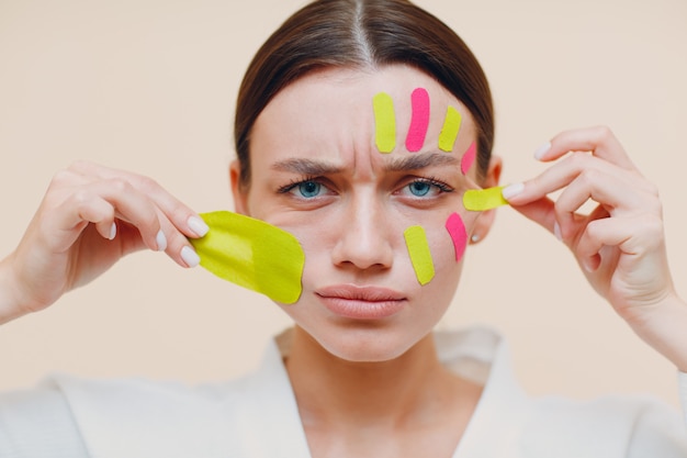 Schöne Frau, die Tape-Lifting-Behandlung im Gesicht anwendet