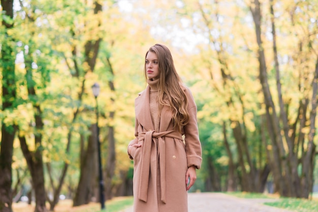 Schöne Frau, die während der Herbstsaison Zeit in einem Park verbringt