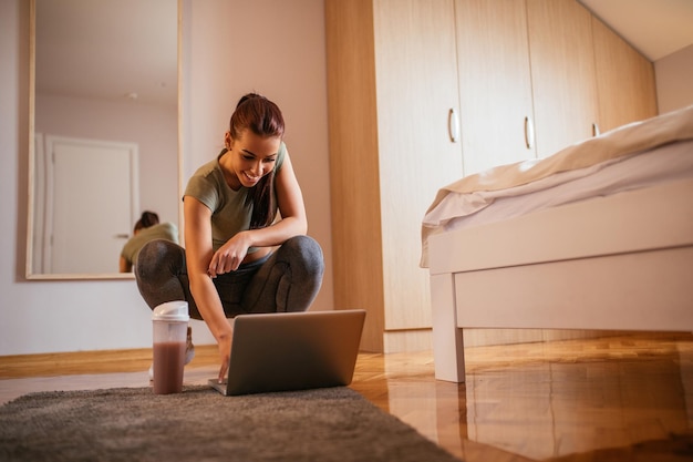 Schöne Frau, die zu Hause mit ihrem Laptop trainiert