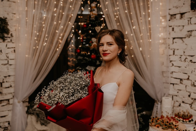 Foto schöne frau feiert neujahr und weihnachten am geschmückten weihnachtsbaum und girlanden