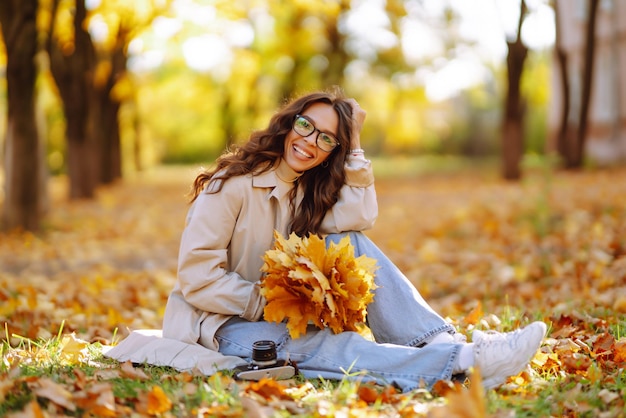 Schöne Frau fotografiert im Herbstwald. Frau genießt Herbstwetter. Lifestyle-Konzept