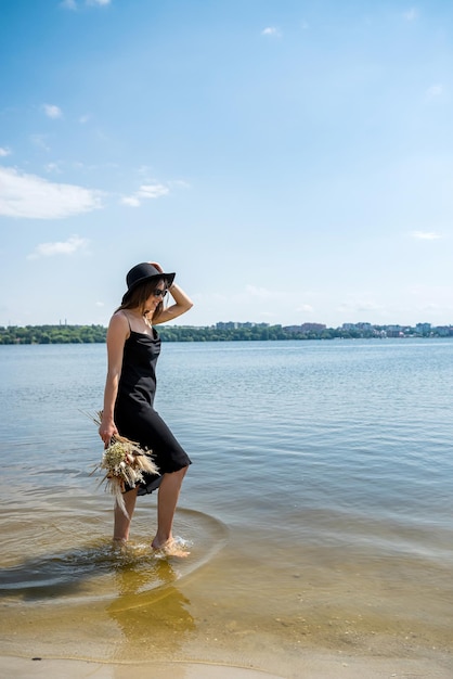 Schöne Frau geht barfuß am warmen Wasser des Sees spazieren