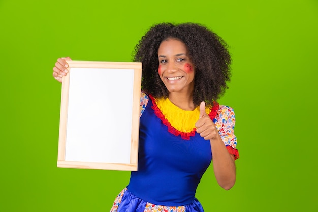 Schöne Frau, gekleidet in festa junina-Outfit, die ein leeres Schild mit Kopierraum hält