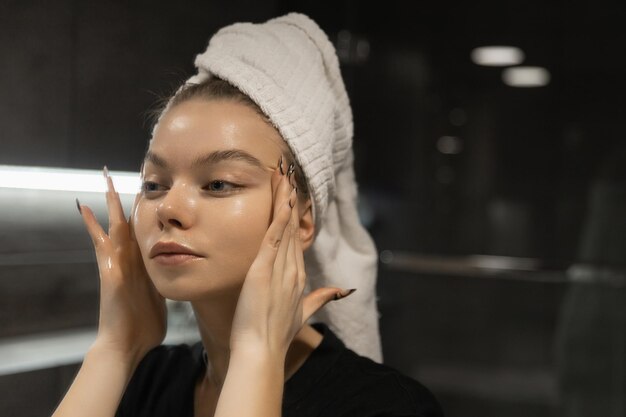 Schöne Frau im Badezimmer malt ihr Gesicht, bevor sie Make-up aufträgt