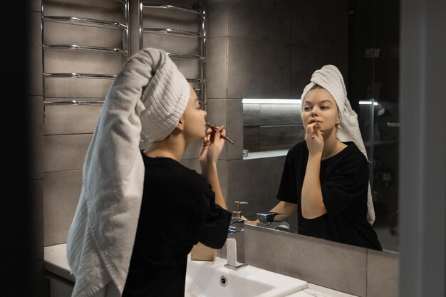 Schöne Frau im Badezimmer stellt sich Lippen nach der Dusche vor und lächelt