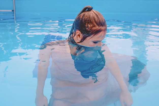 schöne frau im grauen kleid, das im schwimmbad springt