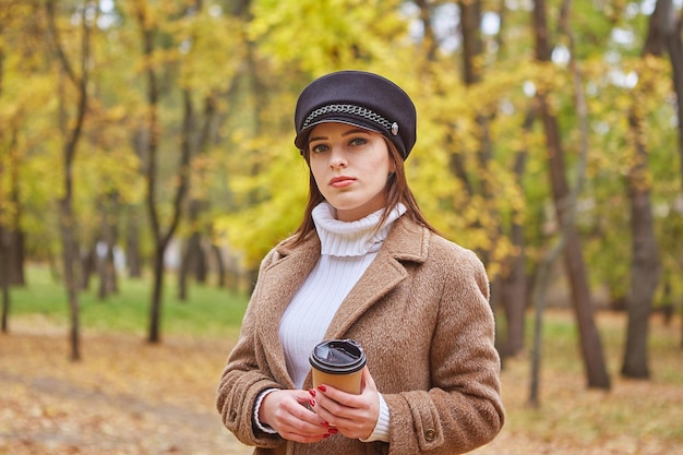 Schöne Frau im Herbstpark mit Kaffee