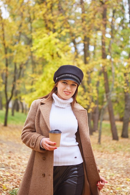 Schöne Frau im Herbstpark mit Kaffee