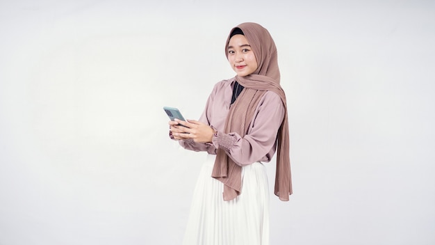 Schöne Frau im Hijab, die Smartphone spielt, isoliert auf weißem Hintergrund