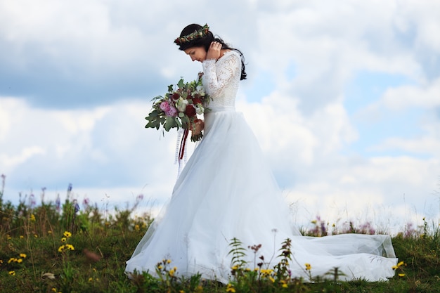 Schöne Frau im Hochzeitskleid, das in den Bergen aufwirft. Fotoshooting vor der Hochzeit