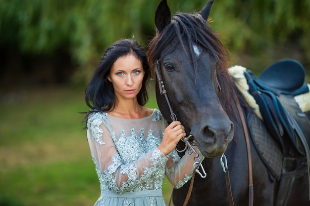 Schöne Frau im Kleid mit Rappe in der Natur