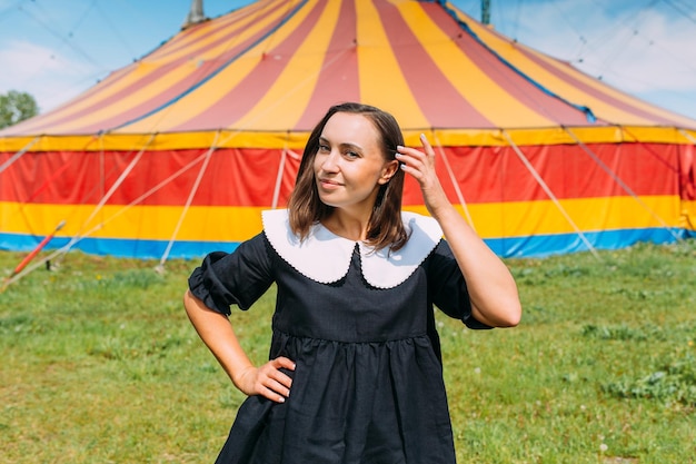 Schöne Frau im Kleid posiert an einem sonnigen Tag vor dem Hintergrund des Zirkuszeltes