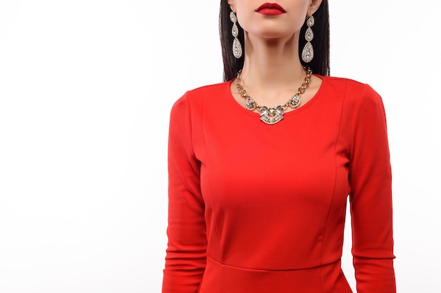 Schöne Frau im roten Abendkleid mit Halskette und Ohrringen
