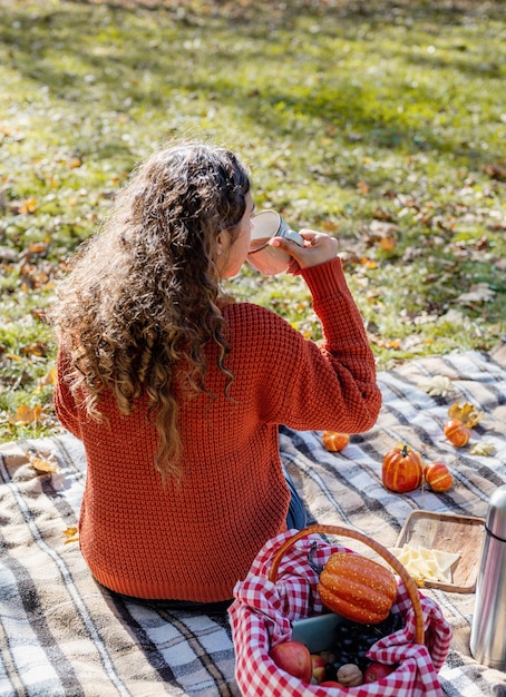 Foto schöne frau im roten pullover auf einem picknick in einem herbstlichen wald