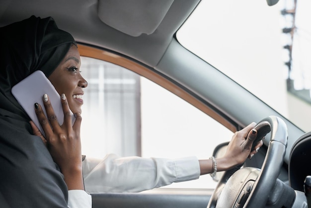 Schöne Frau im schwarzen Hijab, die im Auto telefoniert