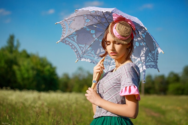 Schöne Frau im Sommer in der Natur mit einem schönen Regenschirm