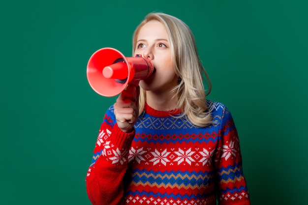 Schöne Frau im Weihnachtspullover hält Megaphon