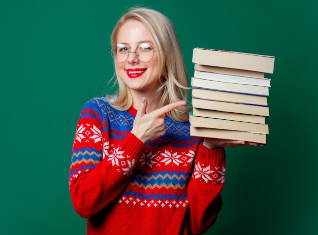 Schöne Frau im Weihnachtspullover mit Büchern