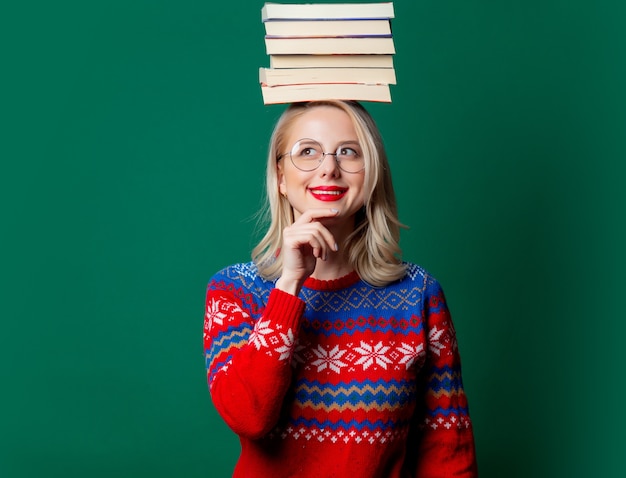 Schöne Frau im Weihnachtspullover mit Büchern