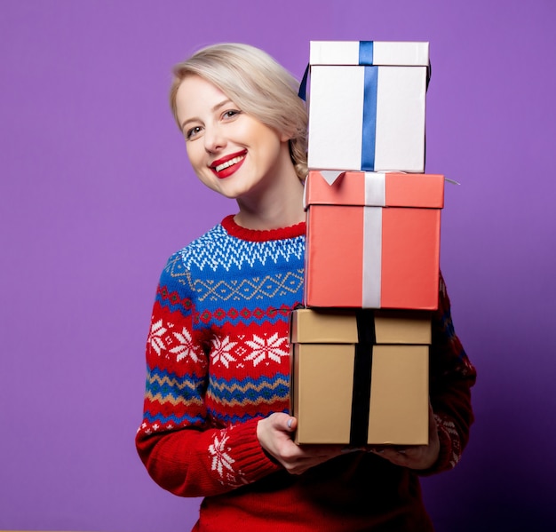 Schöne Frau im Weihnachtspullover mit Geschenkbox