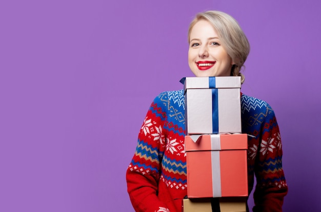 Schöne Frau im Weihnachtspullover mit Geschenkbox