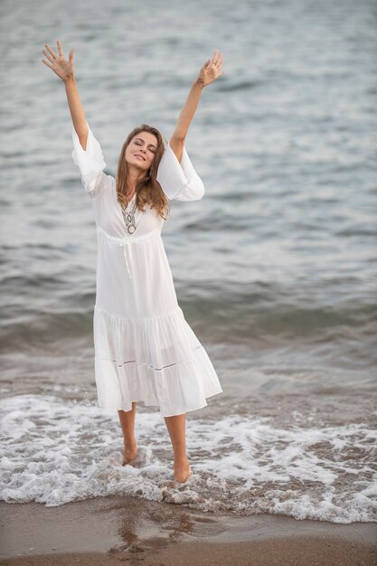 Schöne Frau im weißen Kleid am Meer