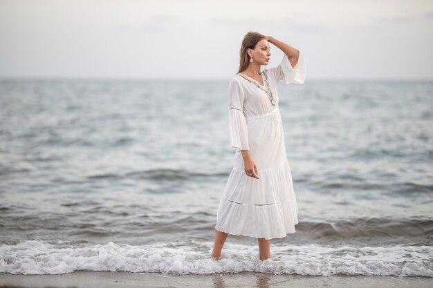 Schöne Frau im weißen Kleid am Meer