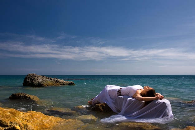 Schöne Frau im weißen Kleid am Meeresstrand